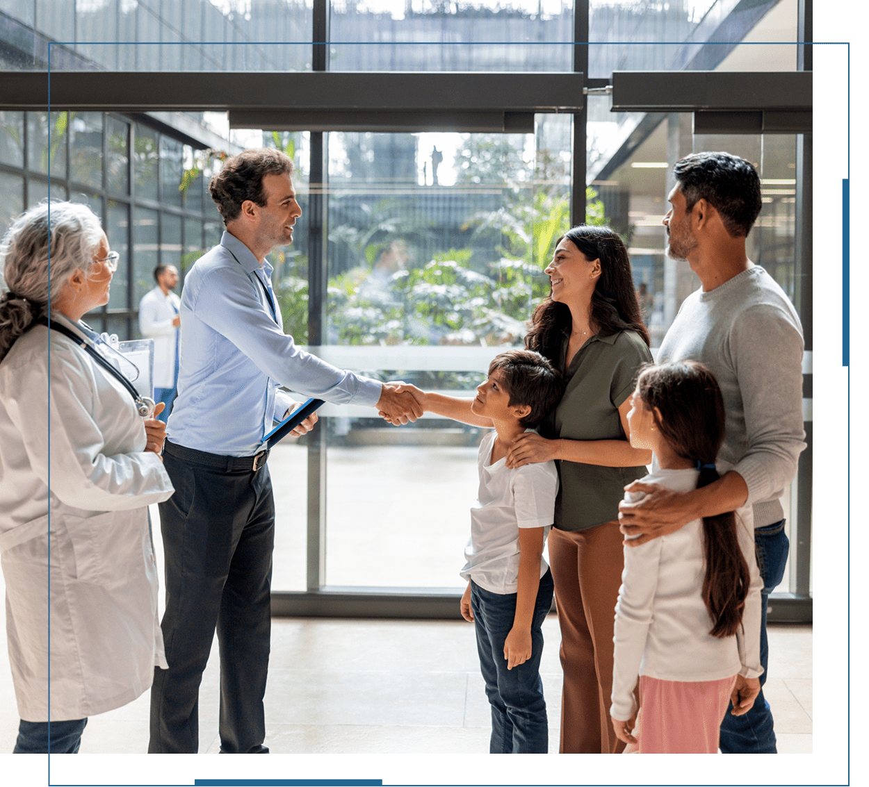 Two men shaking hands while a family with two children looks on.