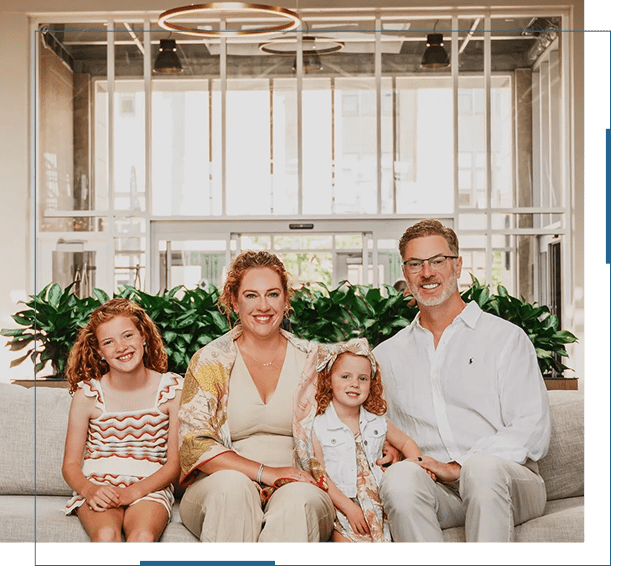 A happy family of four sitting on a couch in a bright, modern living room.